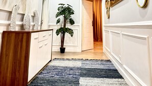 Un pasillo con un escritorio de madera, una planta en maceta y decoración en la pared.