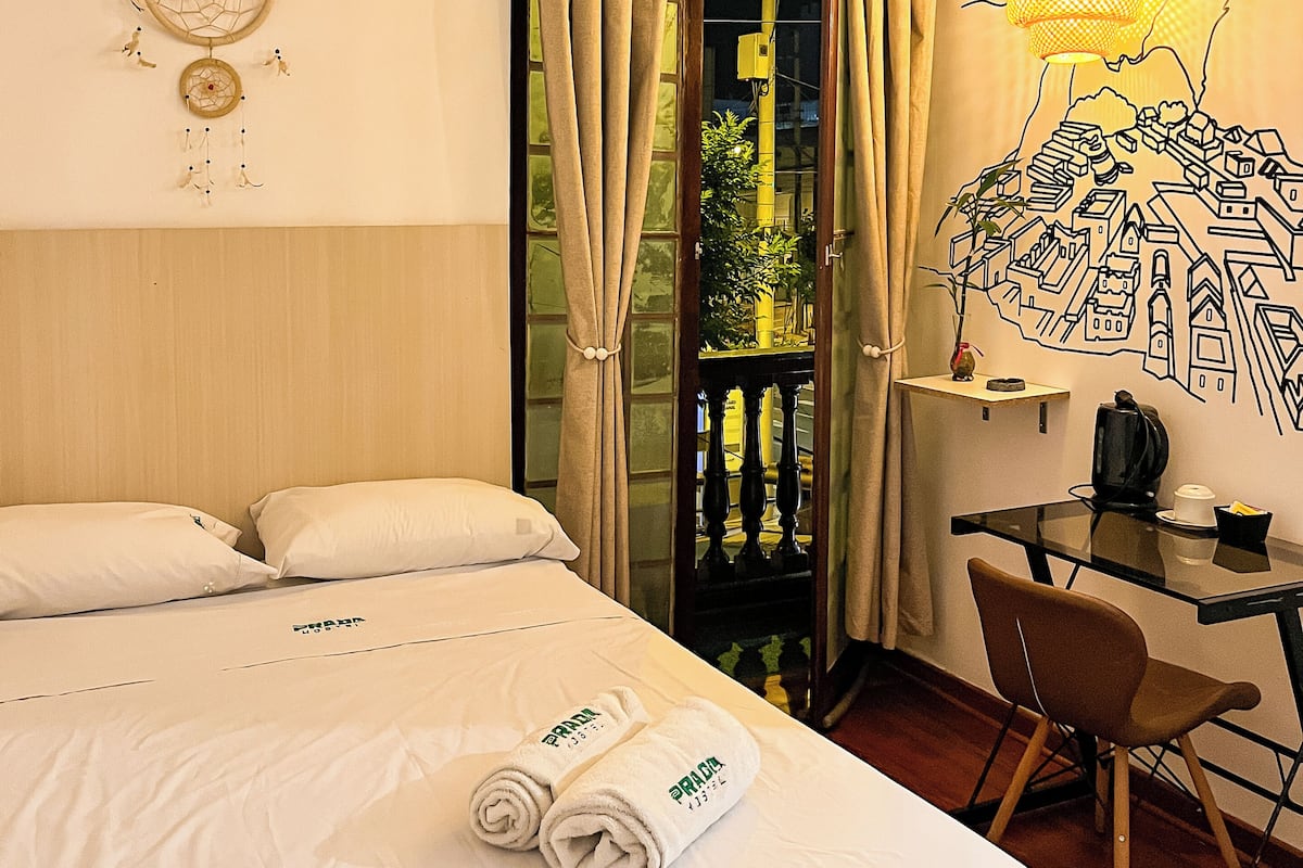 Une chambre d’hôtel équipée d’un lit, d’un bureau, d’une chaise, d’un attrape-rêves et d’une fresque murale.
