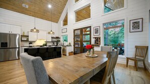 A spacious kitchen with a wooden island, stainless steel appliances, and large windows offering views of the outdoors.