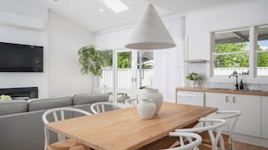 Una cocina moderna con armarios blancos, una mesa de comedor de madera y un amplio ventanal.