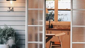 A room with a number '34' on the wall, a potted plant, and a view of a kitchen area with a table and chair.