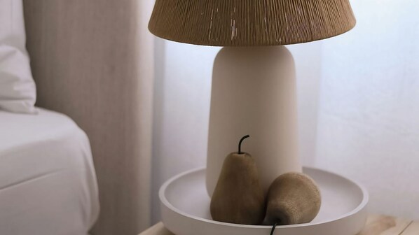 A lamp with a textured shade and two pears on a white table.