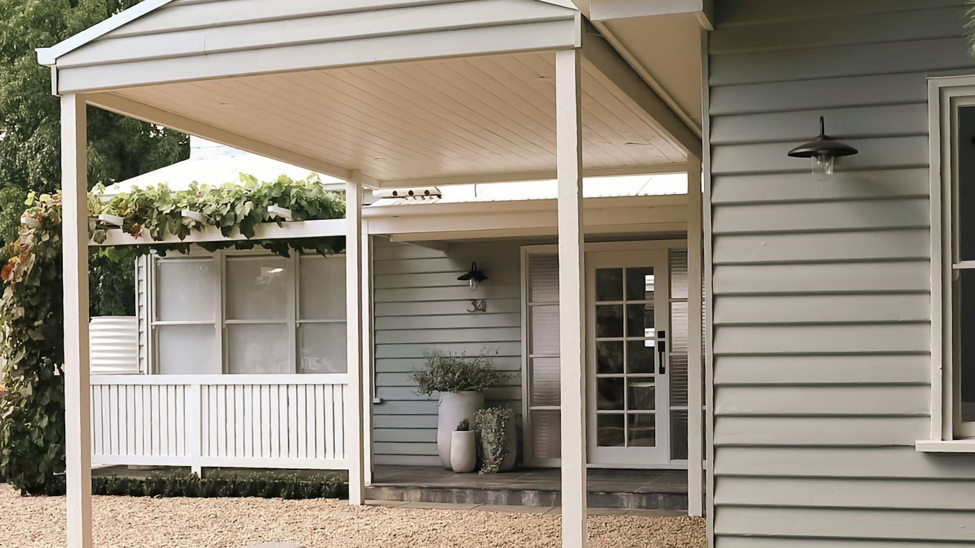 A covered porch with a white railing, a potted plant, and a house number 34.