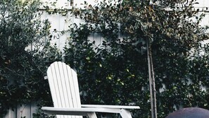 A white chair with a backrest, positioned in front of a wall covered with dense foliage.
