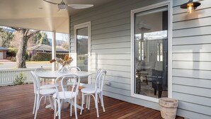 An outdoor patio with a table and chairs, a ceiling fan, and a view of the neighborhood.