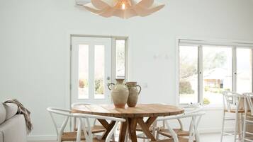 A dining area with a round wooden table, white chairs, and two ceramic vases.