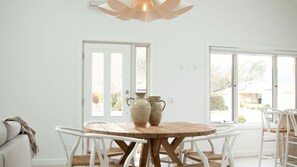 Een eetgedeelte met een ronde houten tafel, witte stoelen en twee keramieken vazen.