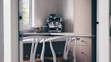 A kitchen with a coffee machine, a window, and a white chair.