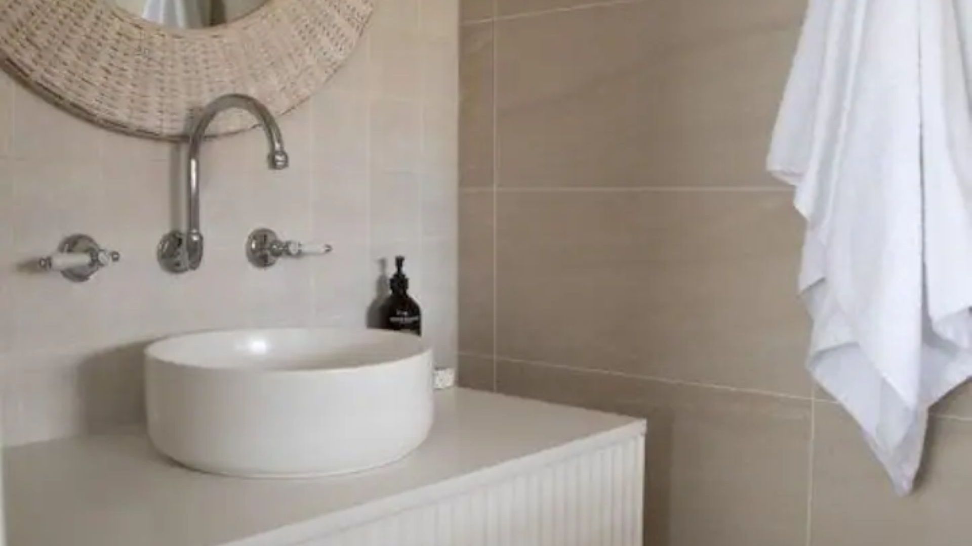 A bathroom with a round sink, a towel rack, and a mirror.