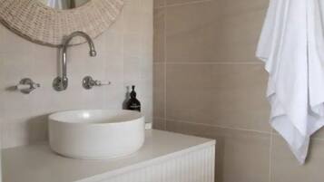 A bathroom with a round sink, a towel rack, and a mirror.