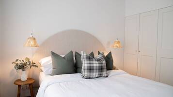 Un lit bien fait, avec une tête de lit, une table de chevet avec une lampe et une armoire.
