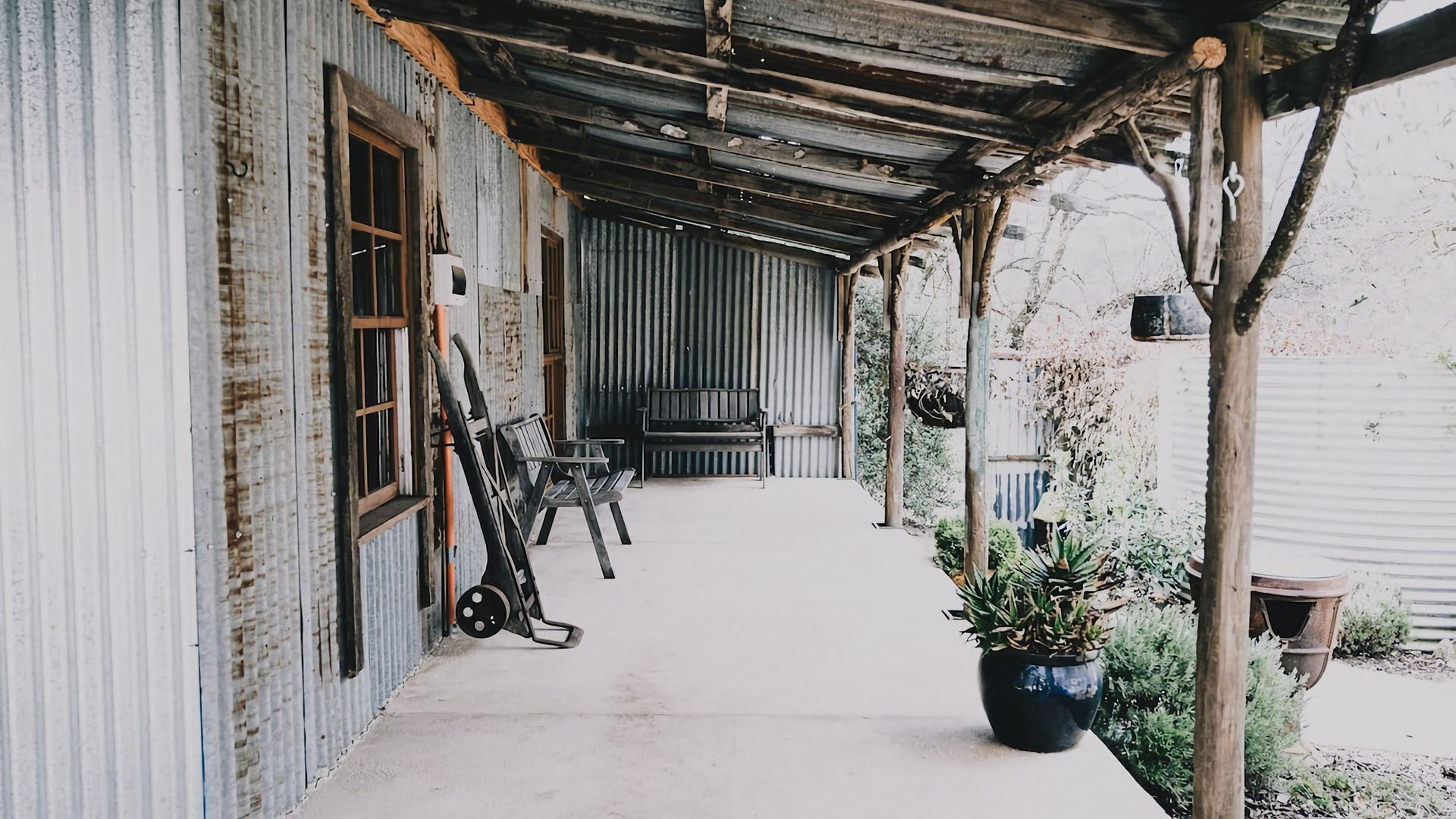 A covered porch with a bench, a bicycle, and a potted plant.