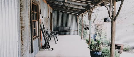 A covered porch with a bench, a bicycle, and a potted plant.