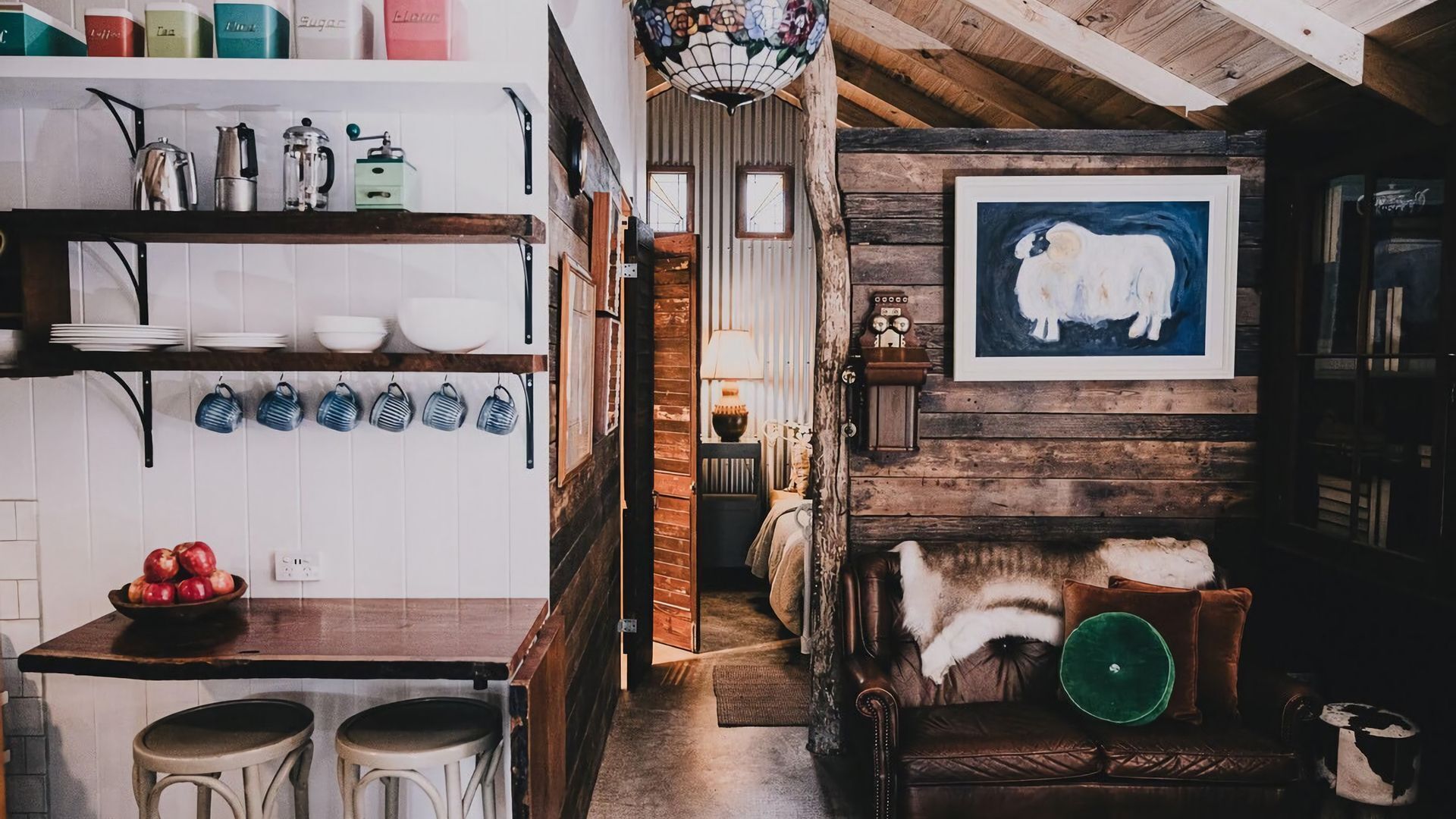 A rustic kitchen with wooden beams, a coffee machine, and a framed artwork of a cow.