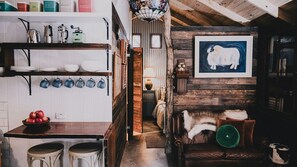 Een landelijke keuken met houten balken, een koffieapparaat en een kunstwerk van een koe.