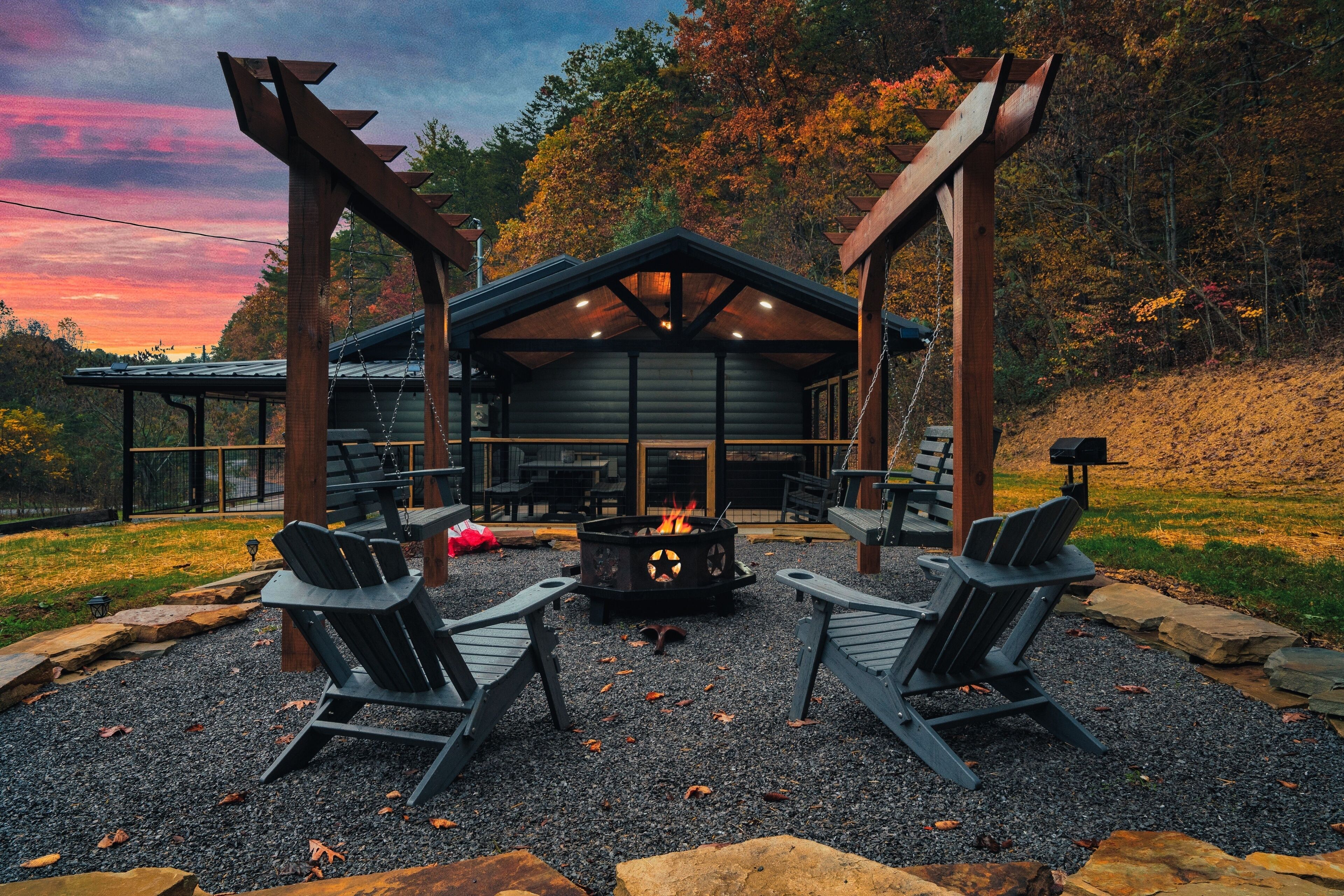 A cabin with a fire pit, two Adirondack chairs, and a pergola structure.