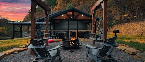 En stuga med en eldstad, två Adirondack-stolar och en pergola.