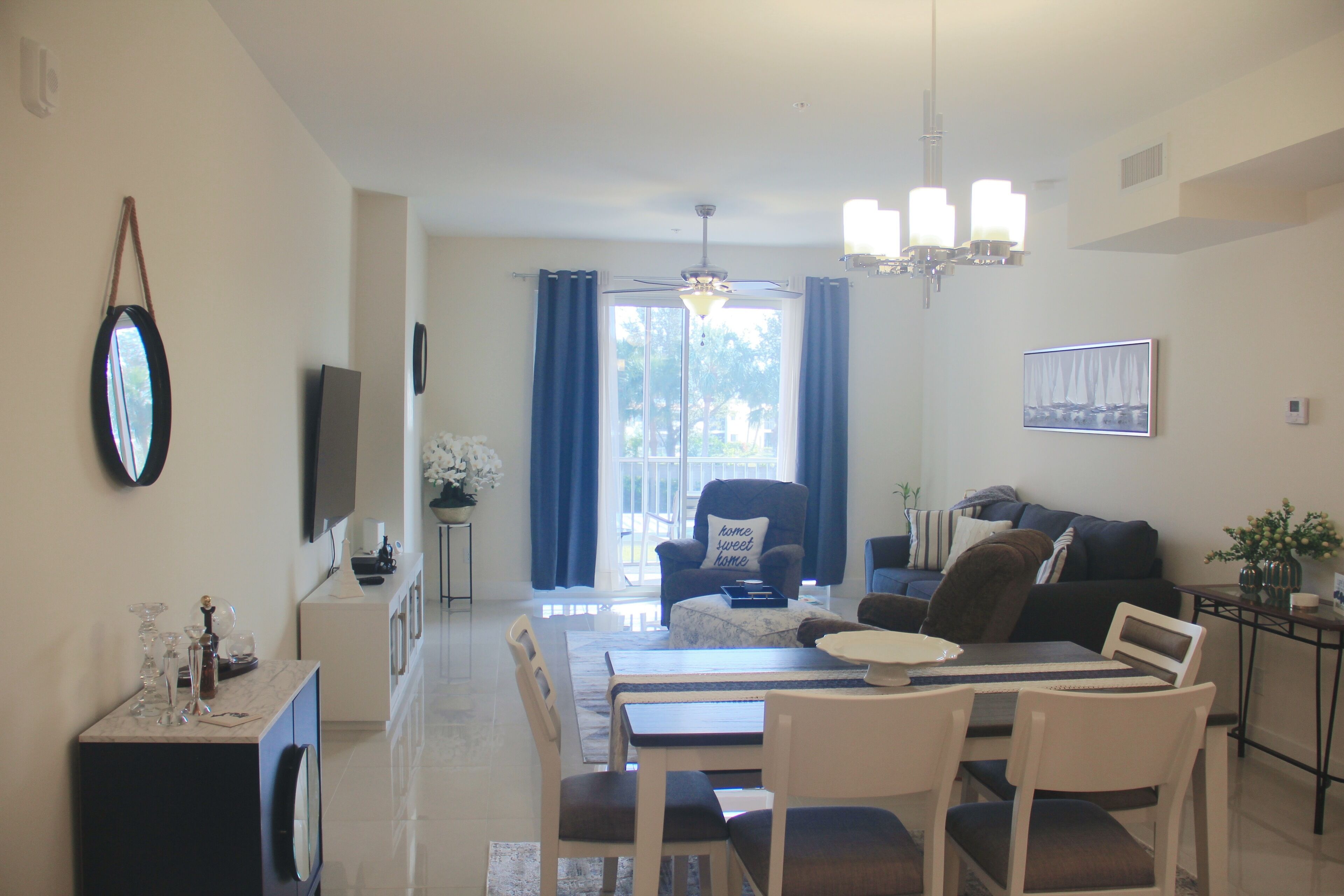 Een moderne woonkamer met een eetgedeelte, een bank, een salontafel en een aan de muur bevestigde televisie.