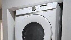 A stacked washer and dryer unit in a corner of a room with a marble floor. - Homestead Green retreat (Homestead)