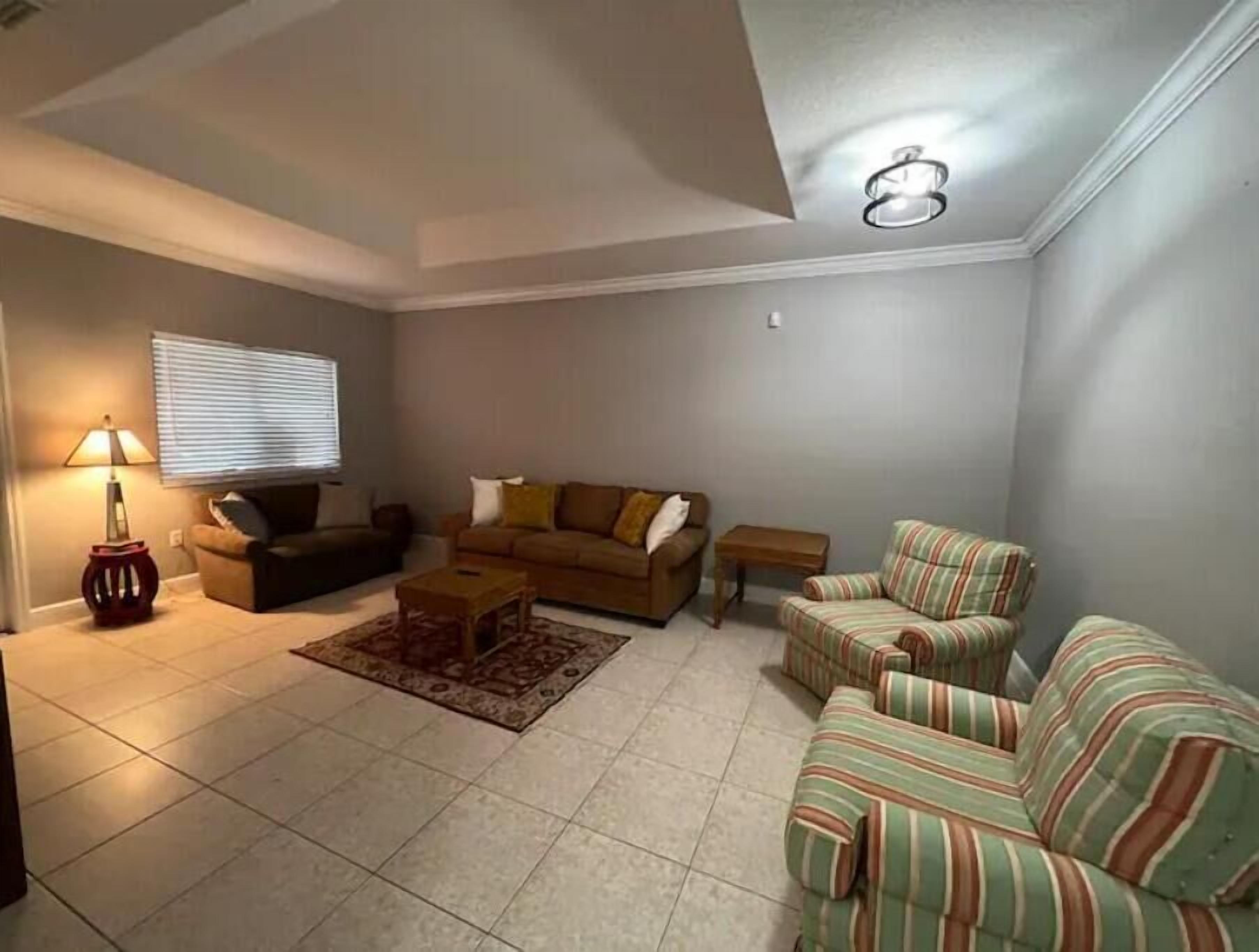 A living room with a sofa set, a coffee table, a lamp, and a window with blinds.