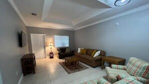 A living room with a sofa set, a coffee table, a lamp, and a television. - Homestead Green retreat (Homestead)