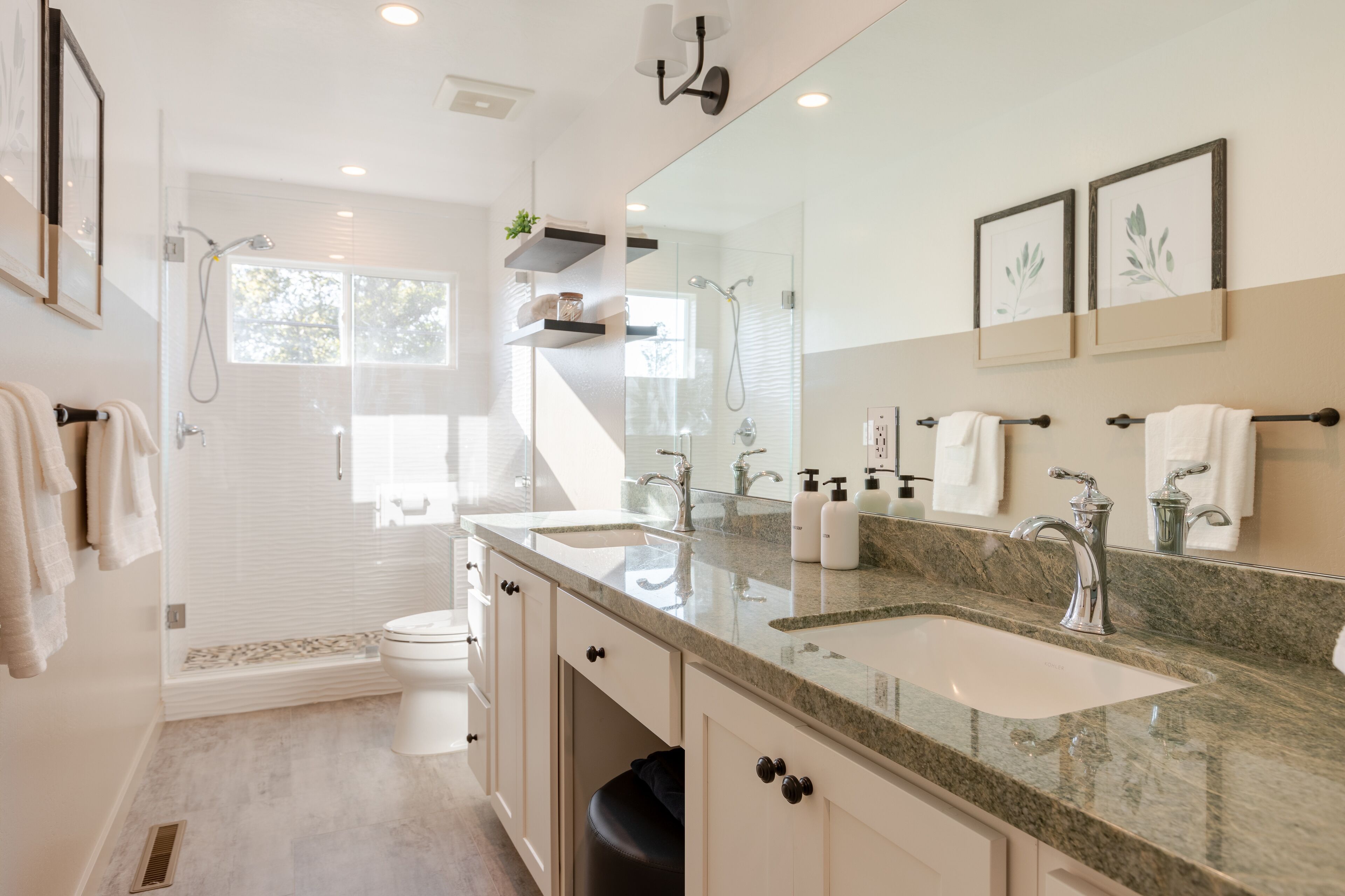 Un baño moderno con lavamanos doble, un espejo grande y zona de ducha.