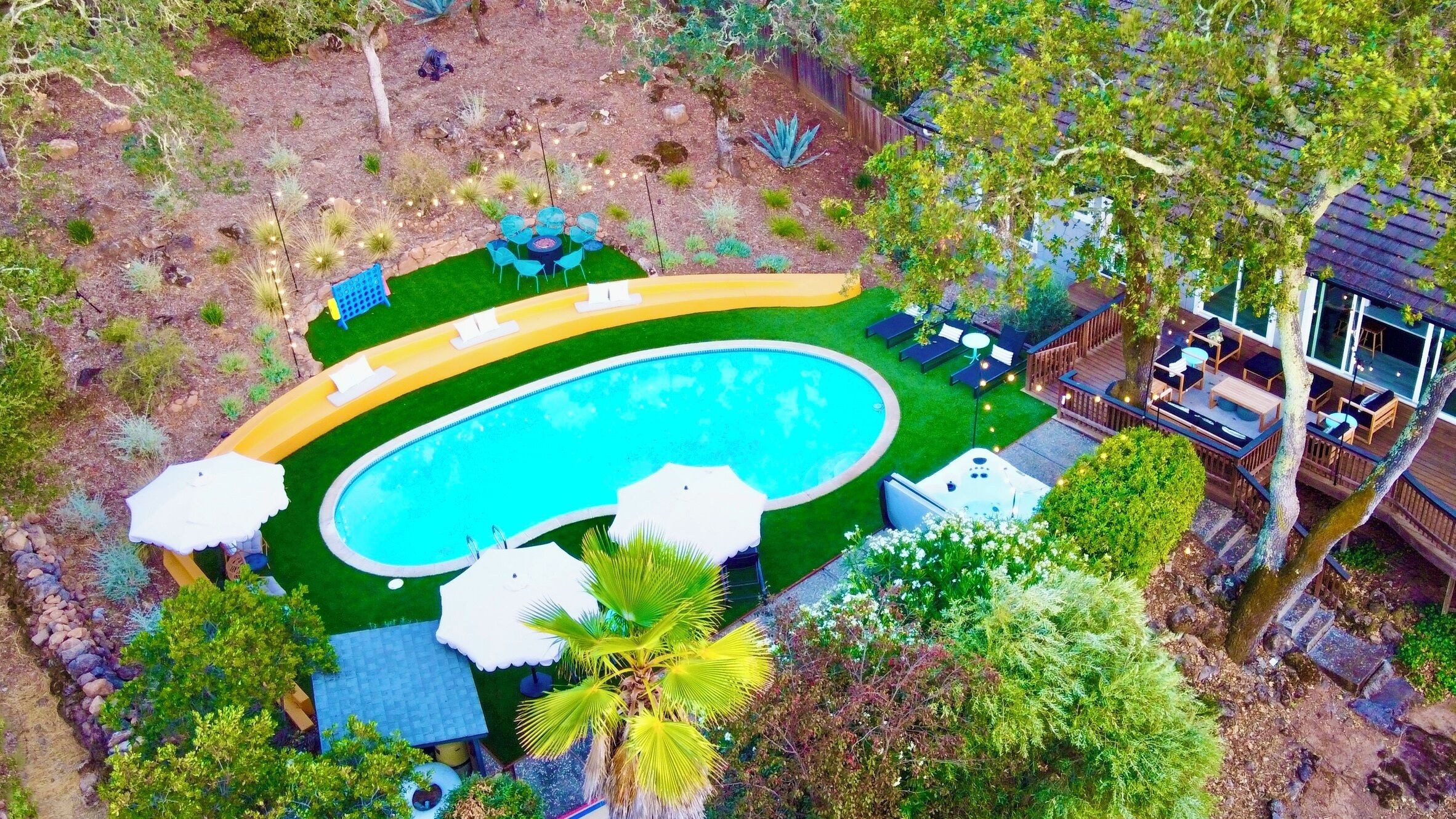 An aerial view of a backyard with a swimming pool, surrounded by a deck and outdoor furniture.