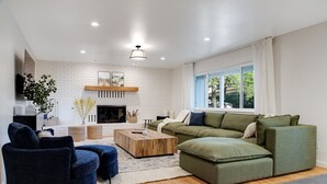 A modern living room with a sectional sofa, a round coffee table, and a fireplace.