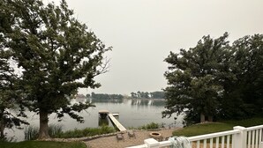 Terrassa al costat d'un llac amb un moll, seients i un camí de pedra.