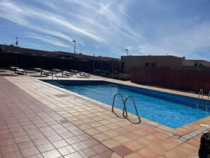 Relax by the pool surrounded by lounge chairs and umbrellas.