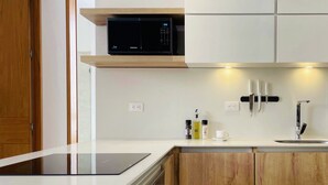 A modern kitchen with a built-in microwave, a coffee maker, and a knife block. - PortaCol By Wynwood House (Bogotá)
