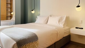 A modern bedroom with a bed, bedside table, and a built-in wooden shelving unit. - PortaCol By Wynwood House (Bogotá)