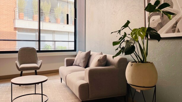 A modern living room with a sofa, a round coffee table, a potted plant, and a chair. - PortaCol By Wynwood House (Bogotá)