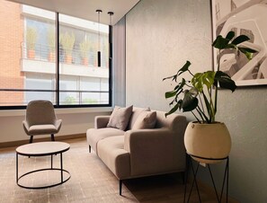 Un salon moderne avec un canapé, une table basse ronde, une plante en pot et un fauteuil.