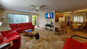 Ein Wohnzimmer mit rotem Sofa, Couchtisch, Fernseher und einem Essbereich mit Stühlen und Tisch.