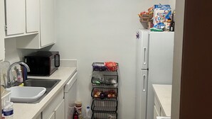 A compact kitchen with white cabinets, a microwave, a sink, a refrigerator, and a small pantry with food items. - Beautiful get away right outside Detroit, peace of mind. Lots of attractions (Taylor)