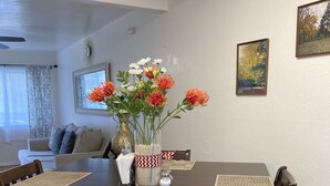 A dining area with a wooden table, chairs, and a vase with flowers.