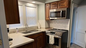 A kitchen with wooden cabinets, a stainless steel microwave, an oven, and a sink. - Explore the Finger Lakes Region from this cozy 3-bedroom home near Geneva, NY. (Waterloo)