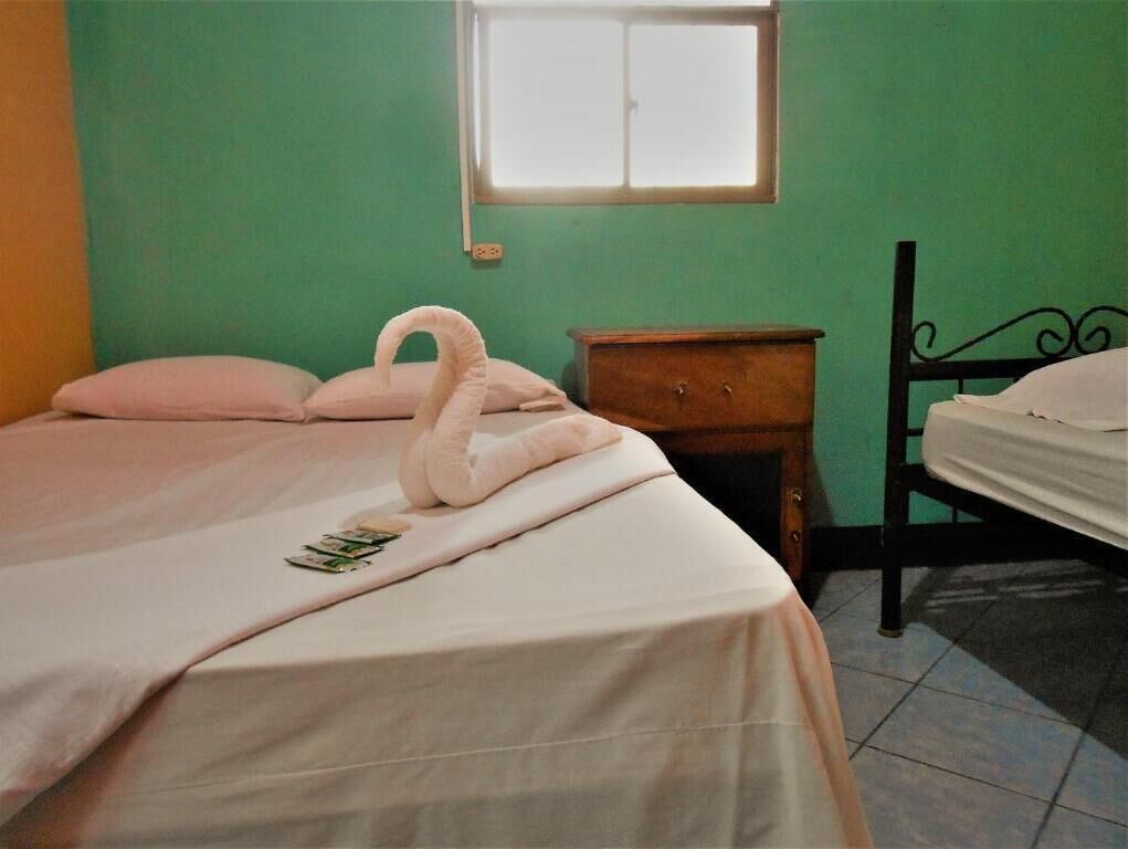 A bedroom with a bed, a nightstand, a dresser, and a window.