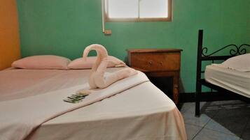 A bedroom with a bed, a nightstand, a dresser, and a window.
