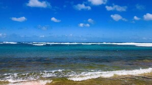 A beach with clear water and waves, under a blue sky with clouds. - Casa Bravo-Premier BEACH VIEW- Shacks Beach-Near Villa Montana Beach Resort (Isabela)
