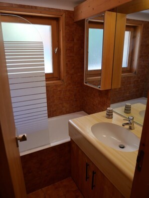 Un baño pequeño con una bañera, un lavabo y un espejo.