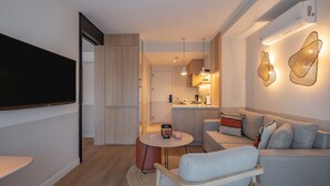 A modern living room with a flat-screen TV, a grey sofa, and a round coffee table. - Oli Hotel And Suites (Konyaalti)