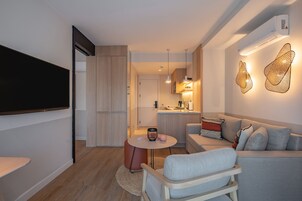 Una sala moderna con televisor de pantalla plana, un sofá gris y una mesa de centro redonda.