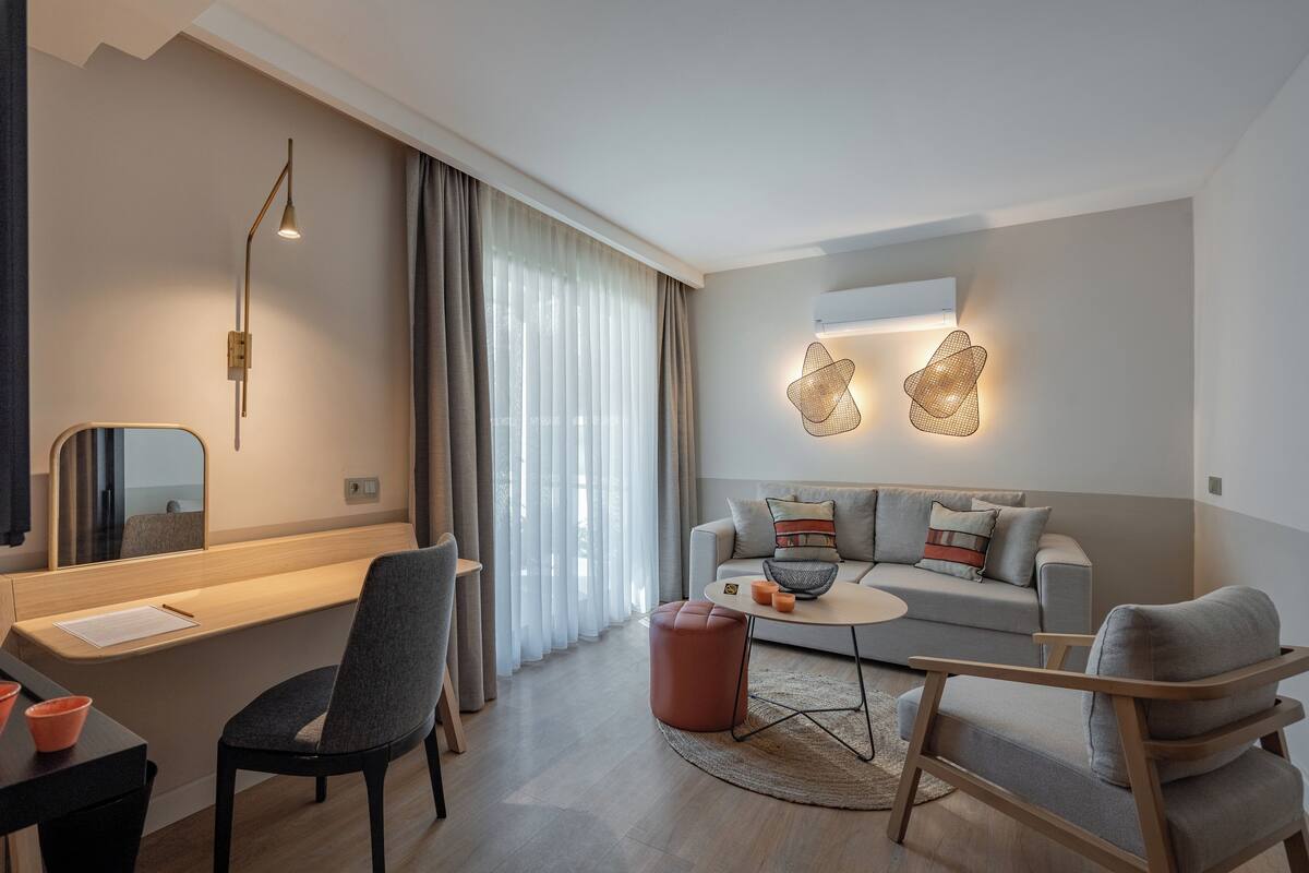 A modern living room with a sofa, chairs, a coffee table, and a desk with a lamp.