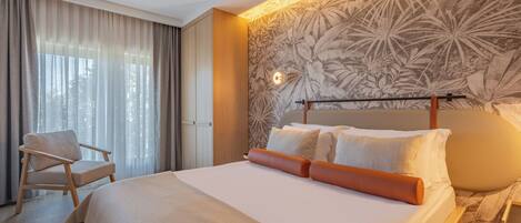 A hotel room with a large bed, a chair, a nightstand, and a wall with a floral pattern.