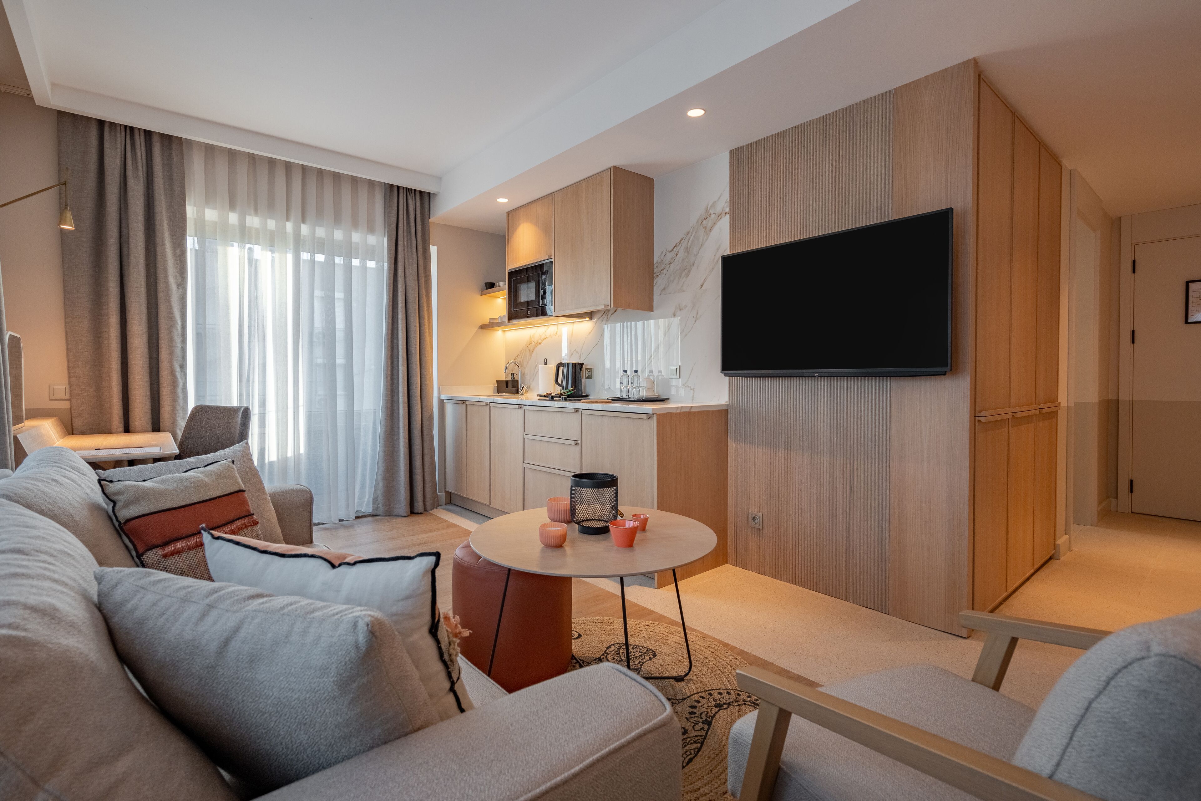 Una sala de estar moderna con un sofá, una mesa redonda de centro y un televisor de pantalla plana montado en la pared.