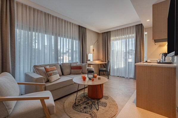 Una sala de estar moderna con sofá, una mesa de centro redonda y una zona de cocina con encimera y electrodomésticos.