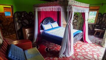 Quarto com cama sob um dossel, tapete com padrão vermelho e branco e parede de pedra.