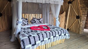 Una cama con dosel, cabecera de madera y manta con estampado geométrico.